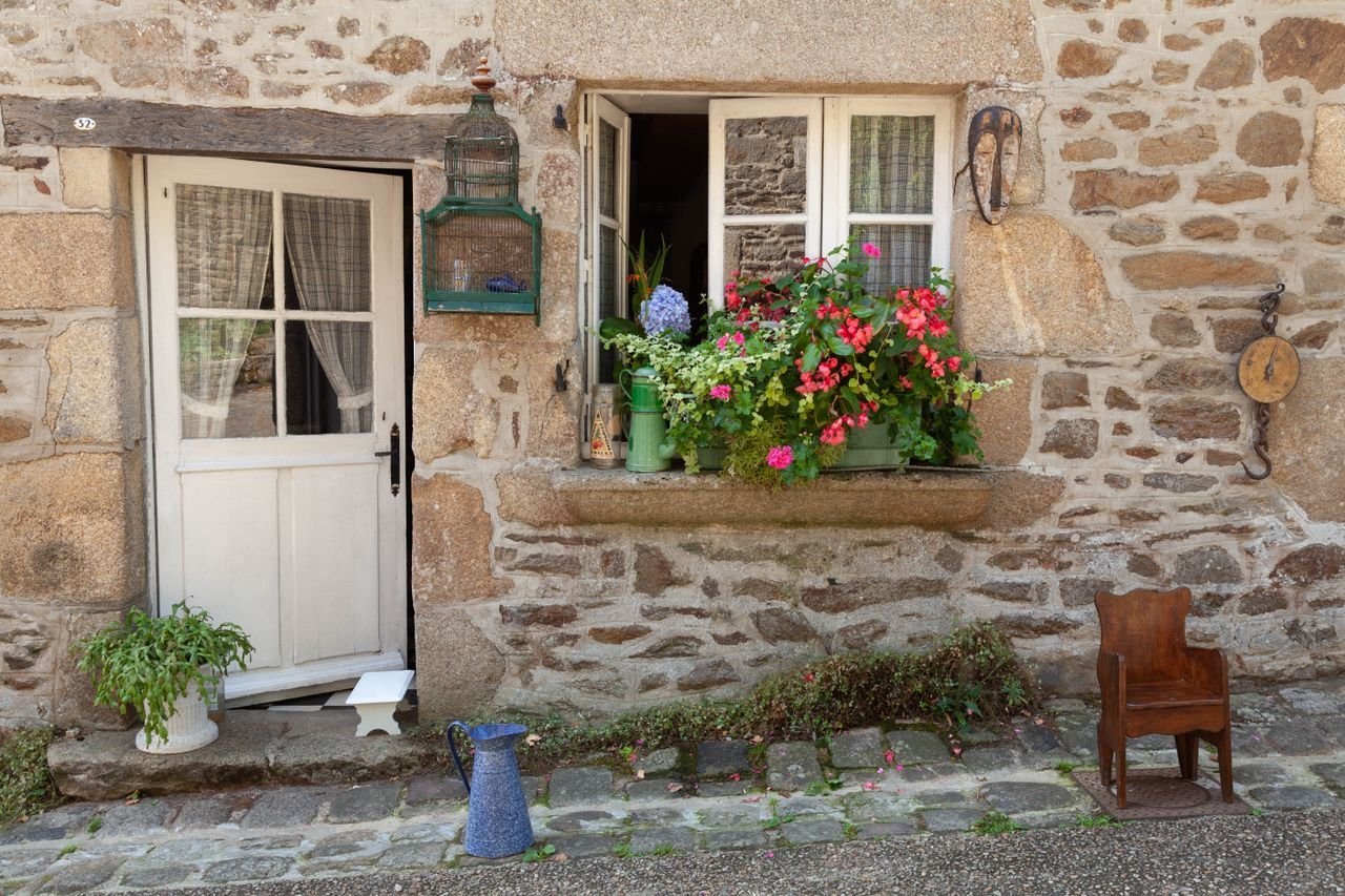 Stone cottage with colorful flowers and vintage decor in Dinan, Brittany, France.
