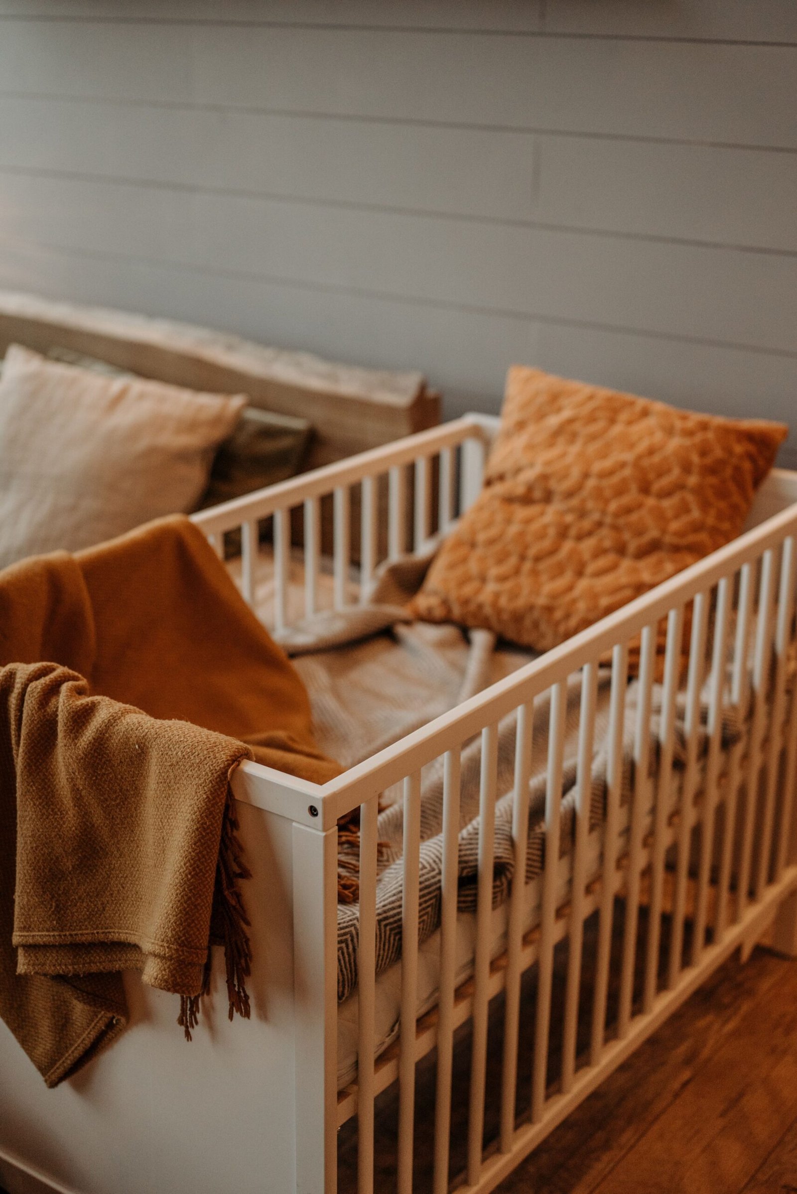 A warm, inviting nursery displaying a stylish crib adorned with textured pillows and a plush blanket.